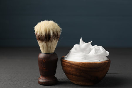Shaving foam and brush on gray wooden table, closeup. Barber's toolsの写真素材