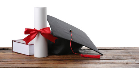 Graduation cap and diploma on wooden table against white background, space for textの写真素材