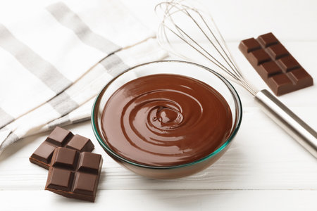 Melted chocolate, pieces white on wooden table, closeupの写真素材