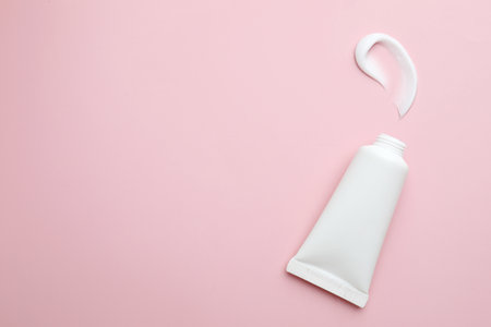 Sample of moisturizing cream and tube on pink background, top view. Space for textの写真素材