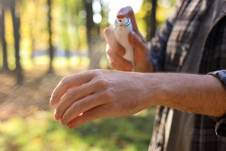 Man spraying tick repellent onto arm in park, closeupの写真素材