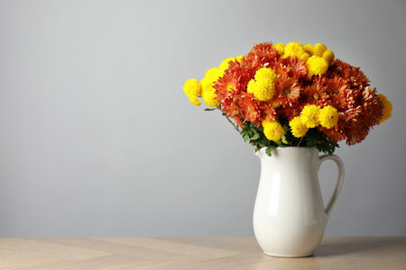 Autumn atmosphere. Vase with beautiful flowers on wooden table, space for textの写真素材
