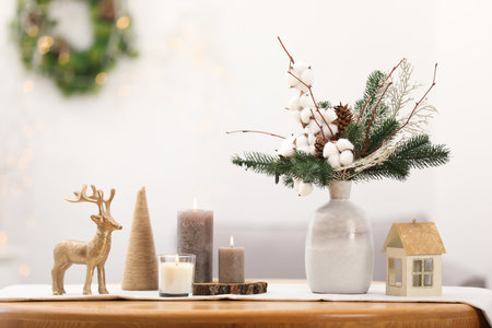 Beautiful composition with fir tree branches in vase and winter decor on wooden table against blurred lights, space for text. Bokeh effectの写真素材
