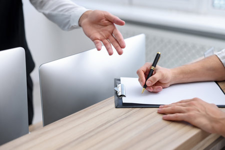 Receptionist working with guest at reception desk in hotel, closeupの写真素材