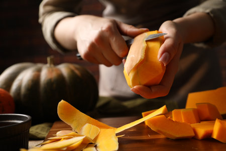 Woman peeling pumpkin with knife at table, closeupの写真素材