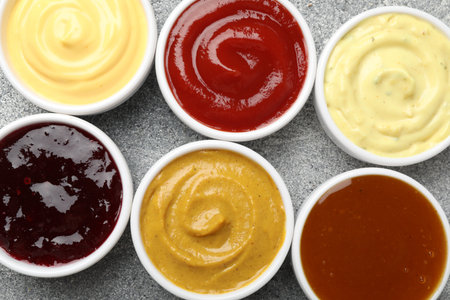 Different tasty sauces in bowls on gray table, flat layの写真素材