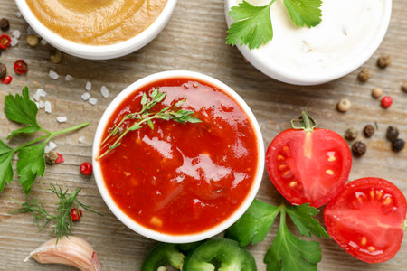 Different sauces, spices and parsley on wooden table, flat layの写真素材