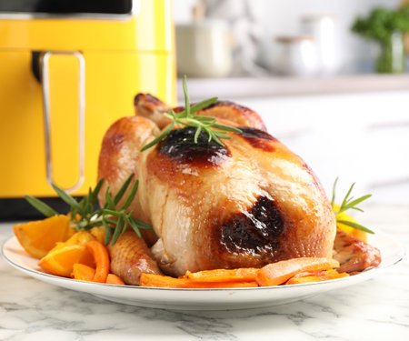 Tasty roasted chicken with rosemary and vegetables on white marble table, closeupの写真素材