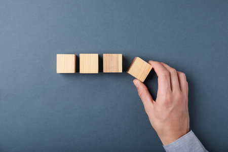 Man with wooden cubes on gray background, top viewの写真素材