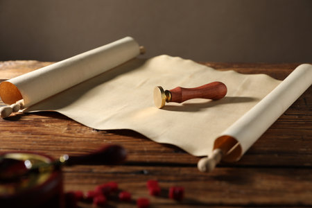 Old paper scroll, stamp and pieces of wax on wooden table, closeupの写真素材