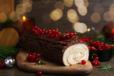 Delicious Yule log (traditional Christmas cake) with redcurrant on wooden table, closeupの写真素材