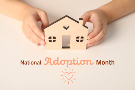 National Adoption Month poster with heart illustration. Child holding model of house on beige background, closeupの写真素材