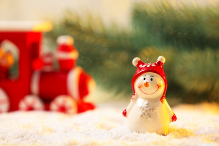 Cute decorative snowman on artificial snow against blurred background, closeup. Space for textの写真素材