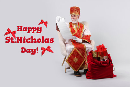 Saint Nicholas with gift list and bag full of boxes on white background. Greeting card designの写真素材