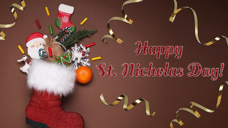 Happy St. Nicholas Day greeting card design with red boot full of sweet treats and decor on brown background, top viewの写真素材