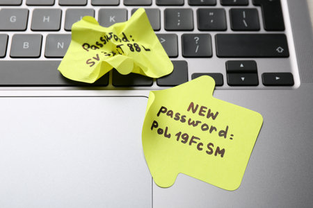 Changing password. Paper notes with new and old passwords on laptop, closeupの写真素材