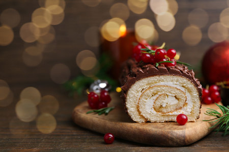 Delicious Yule log (traditional Christmas cake) with redcurrant on wooden table, closeup. Space for textの写真素材