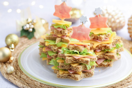 Christmas food. Fir trees made of bread, cheese, ham, lettuce and decor on table, closeup. Bokeh...