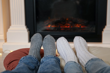 Couple in warm socks resting near fireplace at home, closeupの写真素材