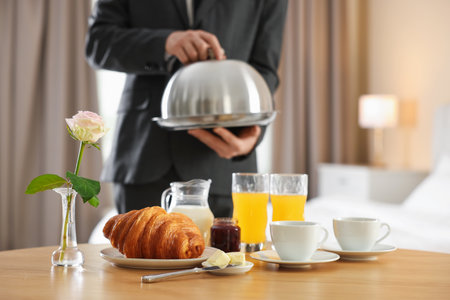Waiter serving breakfast on wooden table in hotel room, closeupの写真素材