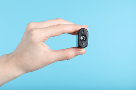 Woman with hidden camera on light blue background, closeupの写真素材