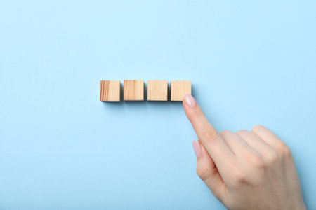 Woman with wooden cubes on light blue background, top viewの写真素材