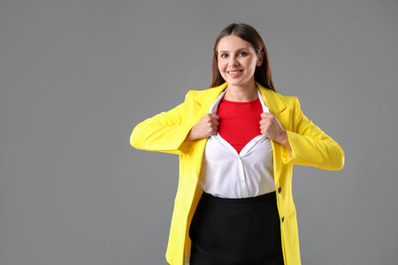 Businesswoman wearing superhero costume under her clothes on gray background. Space for textの写真素材