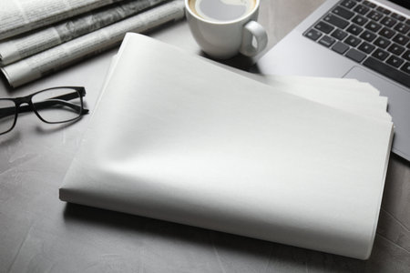 Newspapers, laptop, coffee and glasses on gray table, closeup. Mockup for design