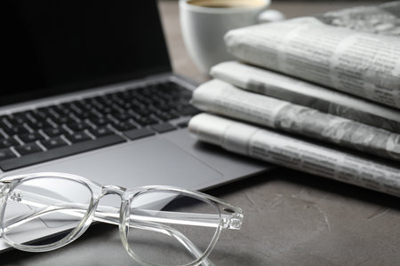 Newspapers, laptop and glasses on gray table, closeupの写真素材