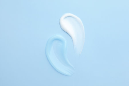 Samples of different cosmetic products on light blue background, flat layの写真素材