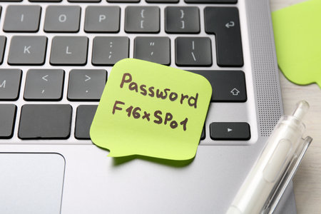 Paper note with password, laptop and pen on table, closeupの写真素材