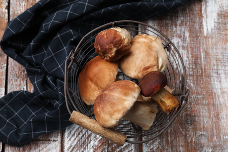 Fresh porcini mushrooms in metal basket on wooden table, top viewの写真素材