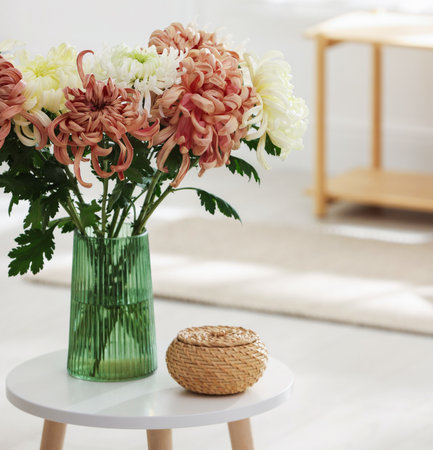 Beautiful chrysanthemum flowers in vase on coffee table indoors, closeupの写真素材