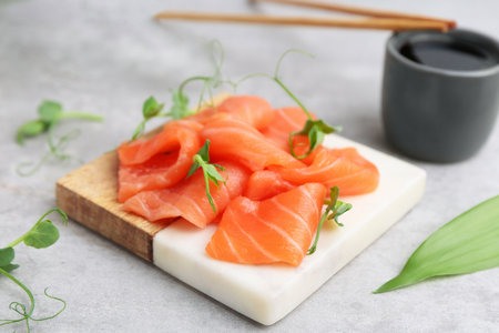 Fresh salmon sashimi with microgreens and soy sauce on gray textured table, closeupの写真素材