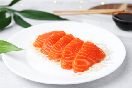 Fresh salmon sashimi with sliced radish on light gray table, closeupの写真素材