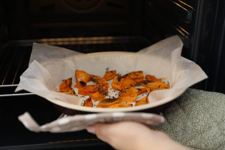 Woman baking dish with baked pumpkin out of oven, closeupの写真素材