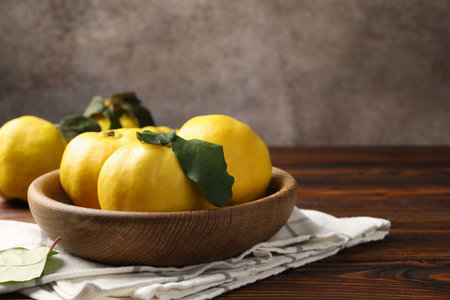 Fresh ripe quinces with leaves on wooden table, closeup. Space for textの写真素材