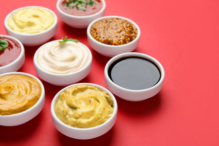 Different sauces in bowls on red background, closeupの写真素材