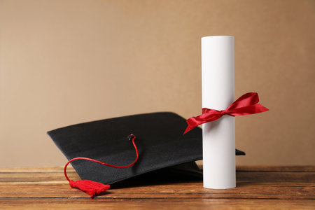 Graduation cap and diploma on wooden table, closeupの写真素材
