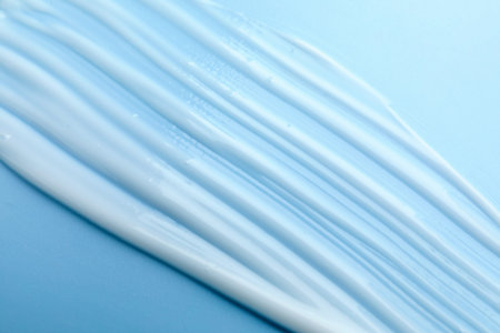 Sample of moisturizing cream on light blue background, top view