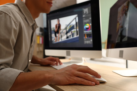 Professional retoucher editing photo on computer at table in office, closeupの写真素材
