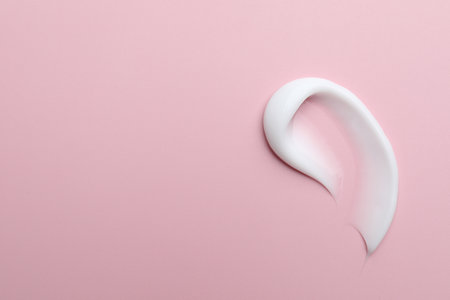 Sample of moisturizing cream on pink background, top view. Space for textの写真素材