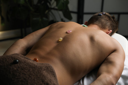 Man undergoing crystal therapy to heal or restore his aura indoors, closeupの写真素材