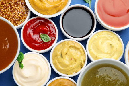 Different sauces and herbs on blue background, flat layの写真素材