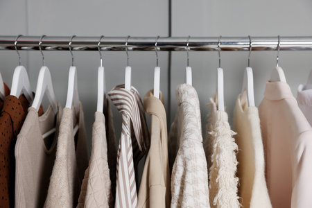 Different clothes hanging on rack near gray wall indoors, closeupの写真素材