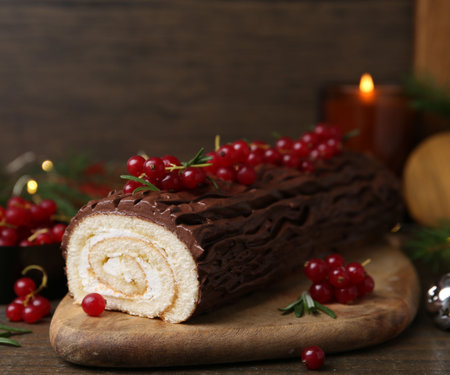 Delicious Yule log (traditional Christmas cake) with redcurrant on wooden table, closeupの写真素材