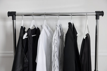 Different clothes hanging on rack near light gray wall indoorsの写真素材