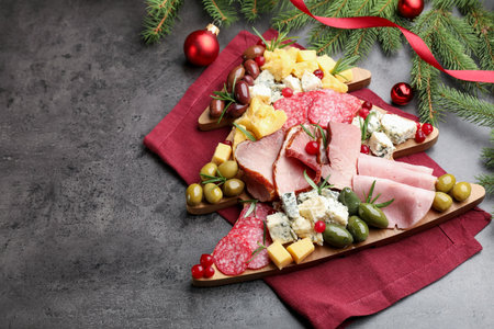 Delicious Christmas Charcuterie board with snacks, fir branches and baubles on gray textured table. Space for textの写真素材