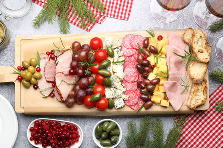 Delicious Christmas Charcuterie board with snacks and fir branches on gray textured table, flat layの写真素材