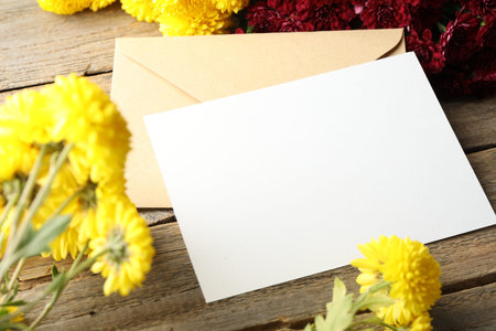 Blank card, envelope and flowers on wooden table, closeup. Mockup for design